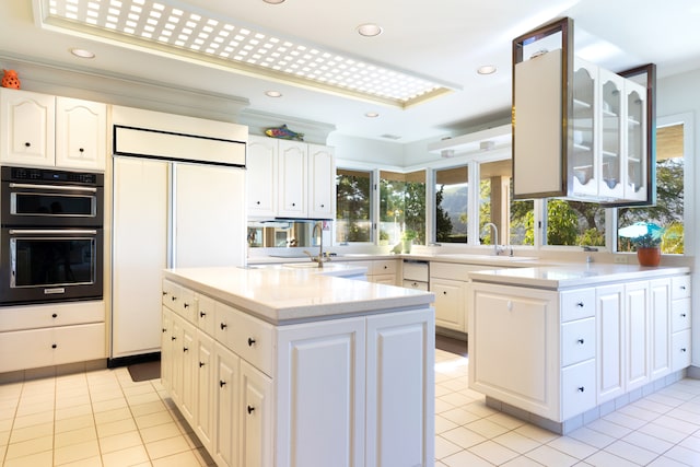 kitchen with black double oven, white cabinetry, light tile patterned floors, and paneled built in fridge