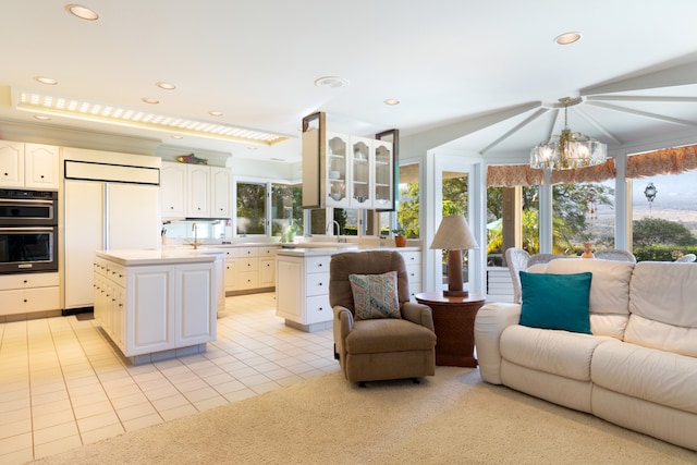 kitchen with pendant lighting, light tile patterned floors, black double oven, paneled refrigerator, and a kitchen island