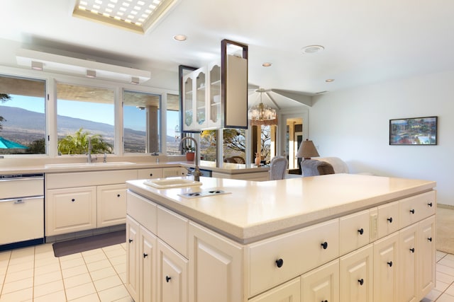 kitchen with light tile patterned flooring, sink, a center island with sink, plenty of natural light, and a mountain view