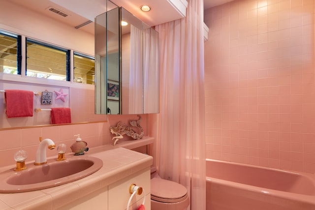 full bathroom with tasteful backsplash, vanity, shower / bath combination with curtain, and toilet