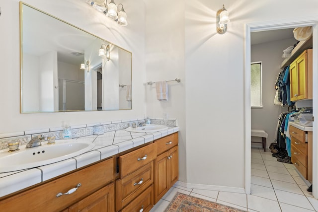 bathroom featuring a shower with door, vanity, and tile patterned floors