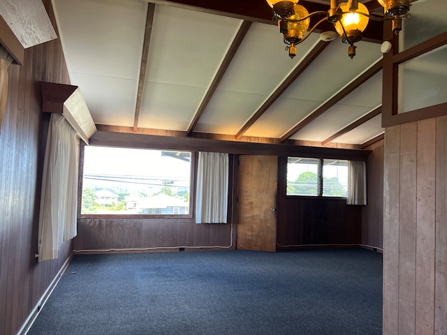 game room with a healthy amount of sunlight, wood walls, and an inviting chandelier