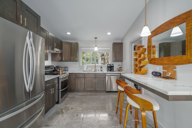 kitchen featuring a kitchen bar, dark brown cabinets, decorative light fixtures, and appliances with stainless steel finishes