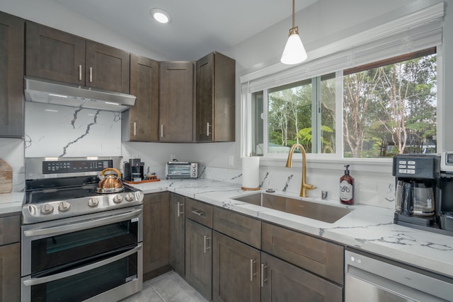 kitchen featuring sink, hanging light fixtures, stainless steel appliances, light stone counters, and lofted ceiling