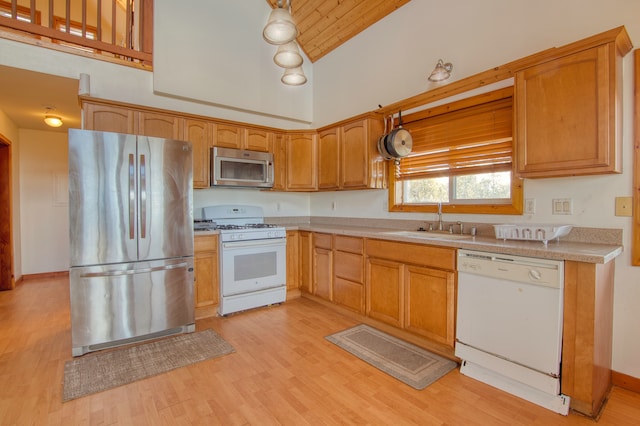 kitchen with appliances with stainless steel finishes, sink, light wood-type flooring, decorative light fixtures, and high vaulted ceiling