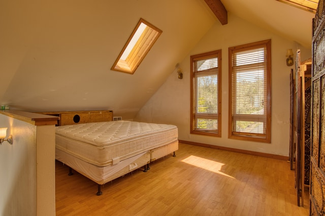 bedroom featuring lofted ceiling with skylight and light hardwood / wood-style flooring