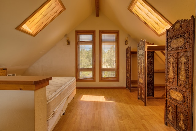 unfurnished bedroom featuring vaulted ceiling with skylight and wood-type flooring