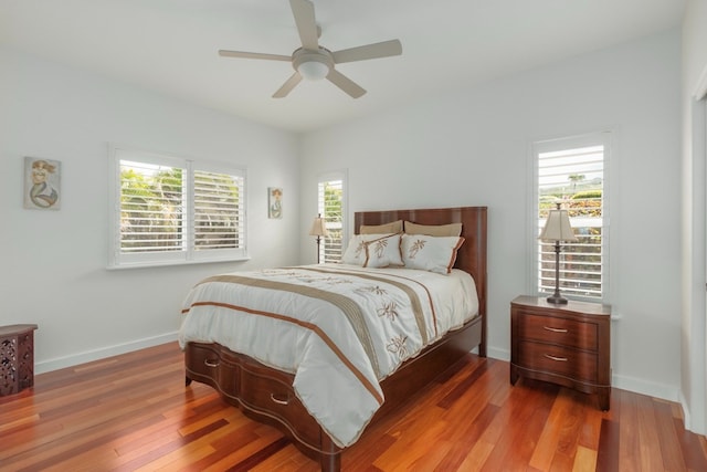 bedroom featuring ceiling fan, wood-type flooring, and multiple windows