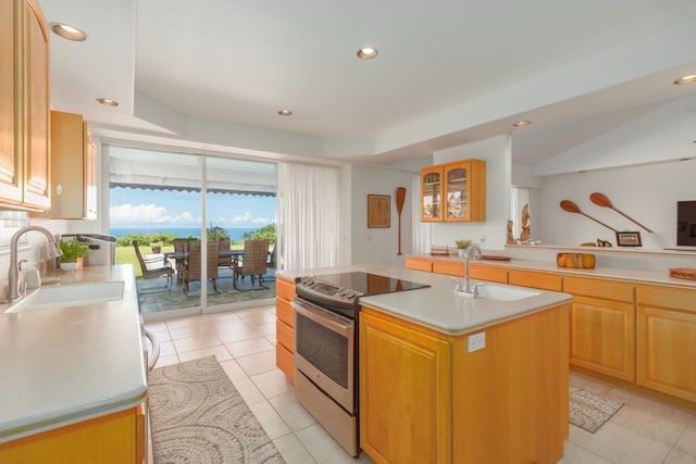 kitchen with light tile patterned floors, stainless steel electric range, sink, and a center island with sink