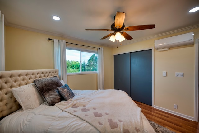 bedroom with a wall mounted AC, a closet, wood-type flooring, crown molding, and ceiling fan