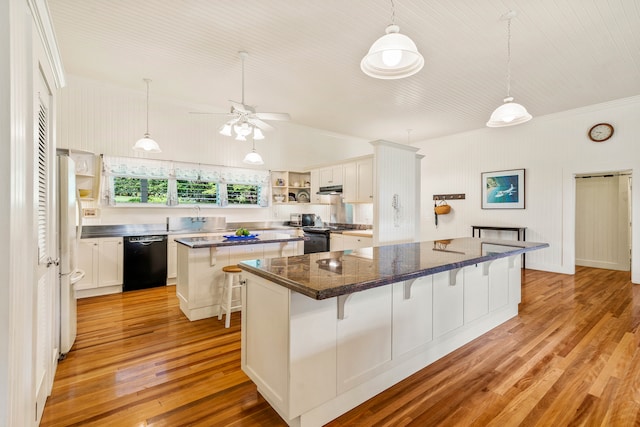 kitchen with a breakfast bar area, black dishwasher, a center island, light wood-type flooring, and white cabinets