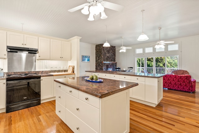 kitchen featuring kitchen peninsula, ceiling fan, light wood-type flooring, black range with electric cooktop, and a center island