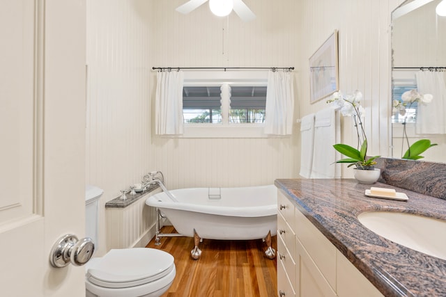 bathroom featuring a tub to relax in, toilet, hardwood / wood-style floors, vanity, and ceiling fan