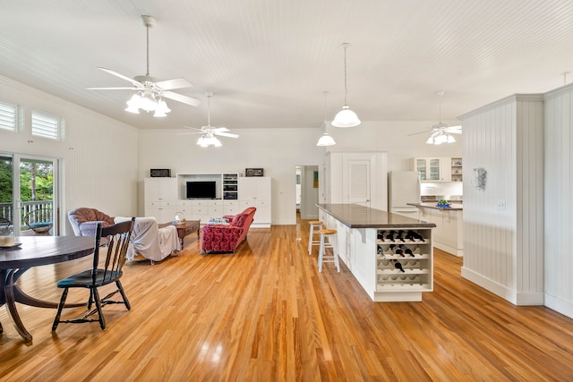 interior space with a breakfast bar, crown molding, white refrigerator, white cabinets, and light hardwood / wood-style floors