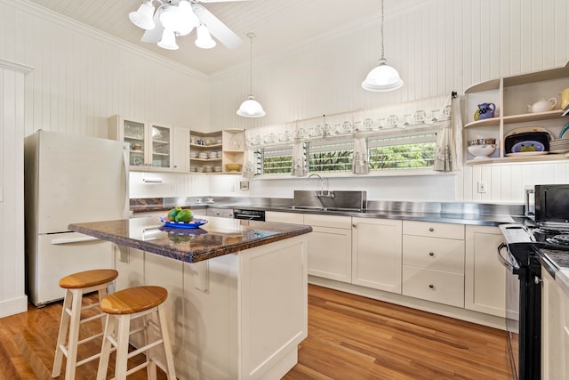 kitchen featuring a kitchen island, white cabinetry, a kitchen bar, white fridge, and sink