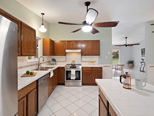 kitchen featuring pendant lighting, sink, decorative backsplash, tile counters, and stainless steel appliances