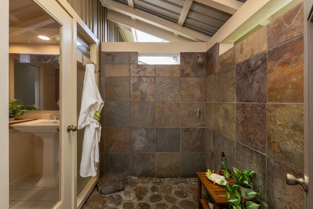 bathroom featuring a tile shower and lofted ceiling with beams