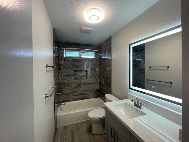 full bathroom with a textured ceiling, hardwood / wood-style flooring, toilet, vanity, and tiled shower / bath combo