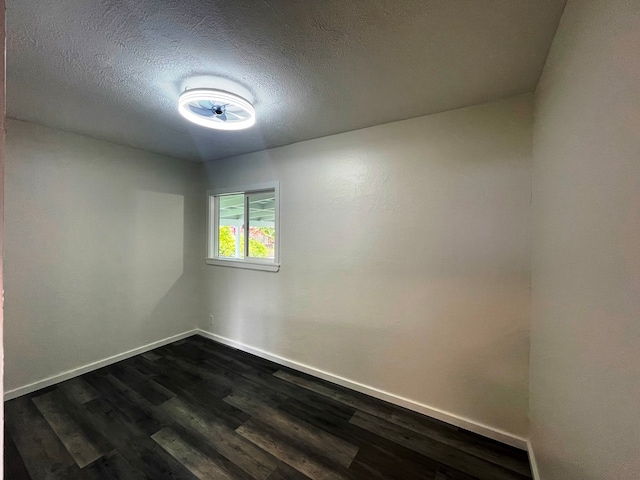 empty room featuring dark wood-type flooring and a textured ceiling