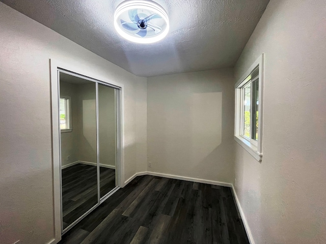 empty room with dark wood-type flooring, ceiling fan, and a textured ceiling