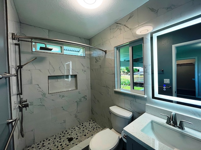 bathroom with a tile shower, toilet, and plenty of natural light