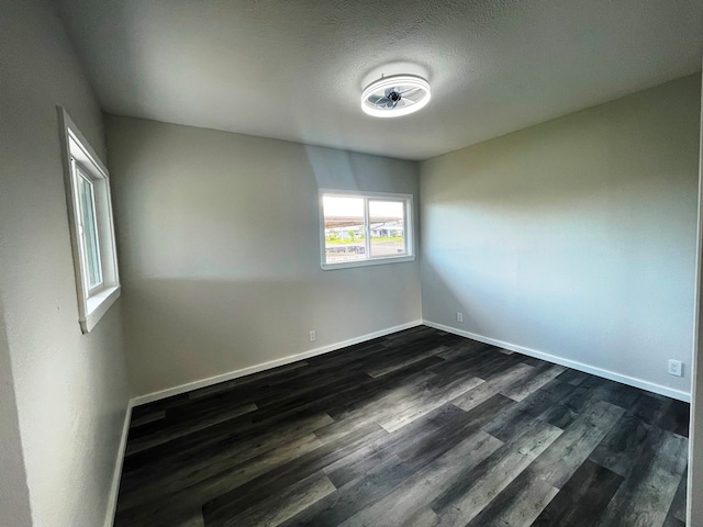 spare room with a textured ceiling and dark hardwood / wood-style flooring