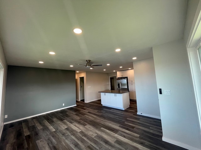 unfurnished living room featuring ceiling fan and dark hardwood / wood-style flooring