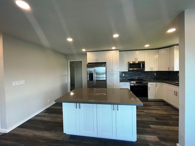 kitchen featuring a center island, white cabinets, stainless steel appliances, and dark wood-type flooring