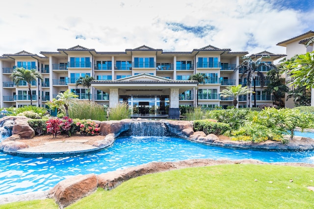 view of pool with pool water feature and a lawn