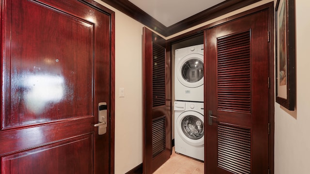 laundry area featuring crown molding, stacked washer / dryer, and light tile patterned floors