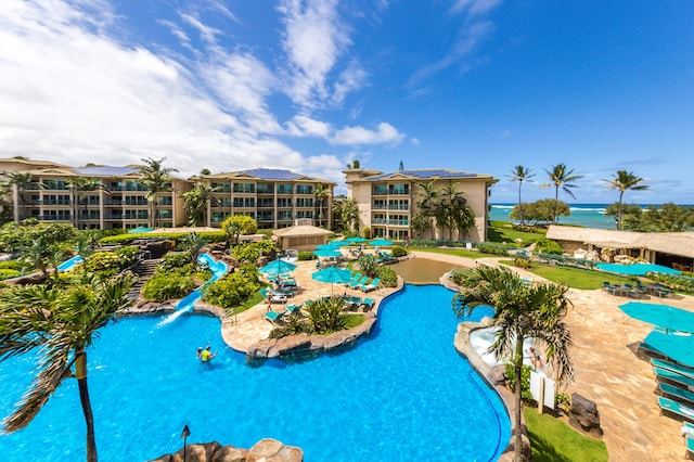 view of pool featuring a water view and a patio