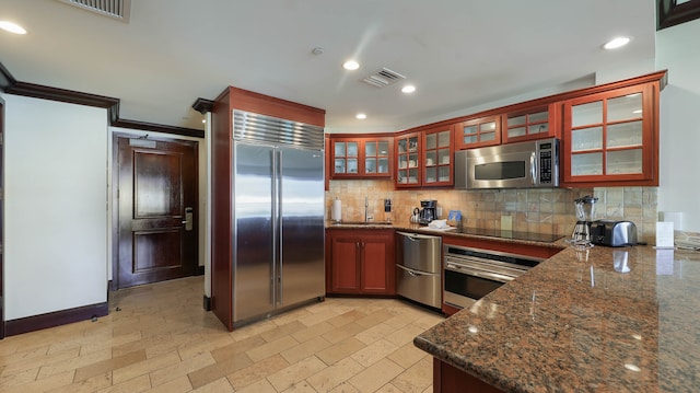 kitchen with sink, appliances with stainless steel finishes, tasteful backsplash, and dark stone counters