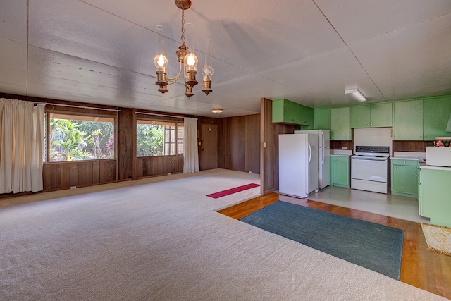 kitchen featuring white appliances, wood walls, green cabinets, decorative light fixtures, and an inviting chandelier