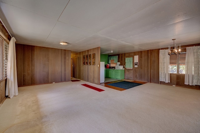 interior space with white fridge, carpet floors, an inviting chandelier, and wood walls