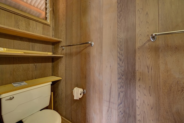 bathroom with toilet and wooden walls