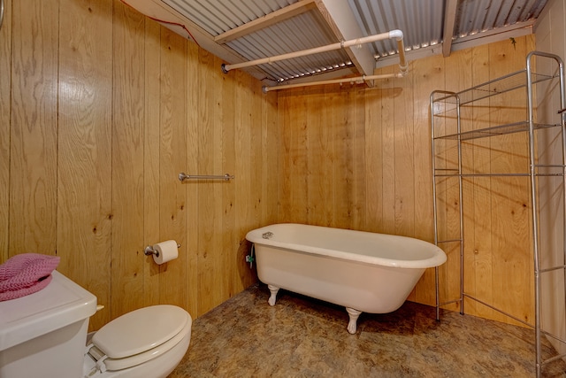 bathroom featuring a bathing tub, toilet, and wood walls