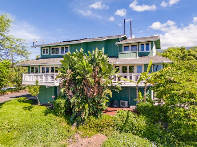 back of property featuring a deck, a lawn, and a balcony