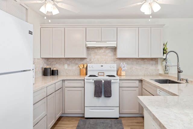 kitchen with white appliances, light hardwood / wood-style floors, decorative backsplash, and sink