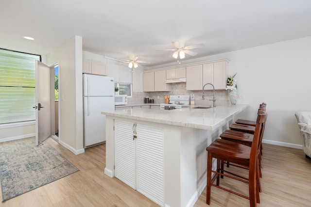 kitchen featuring kitchen peninsula, tasteful backsplash, sink, and white appliances