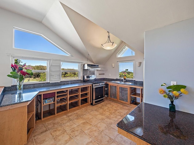 kitchen with lofted ceiling, dark stone counters, hanging light fixtures, stainless steel gas range, and range hood