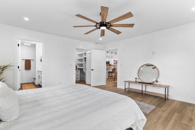 bedroom with ensuite bath, ceiling fan, a spacious closet, light hardwood / wood-style floors, and a closet