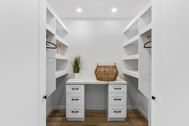 spacious closet featuring built in desk and dark wood-type flooring