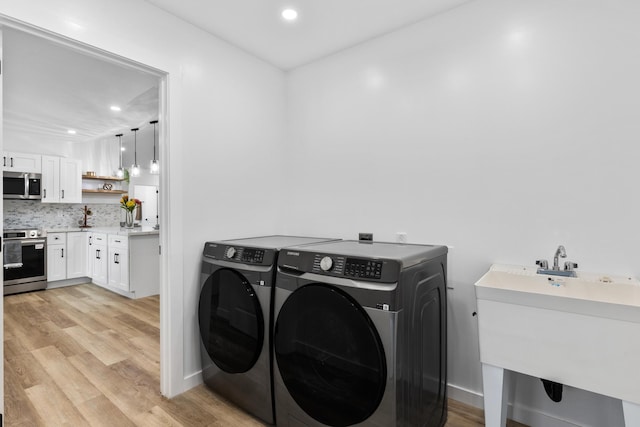 washroom featuring separate washer and dryer, sink, and light hardwood / wood-style flooring