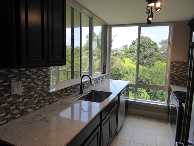 3811 Edward Rd Unit 1202, Princeville, HI 96722 - kitchen with a sink, light tile patterned floors, dark cabinetry, decorative backsplash, and light stone counters