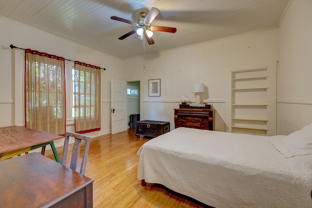 bedroom featuring ceiling fan, wooden ceiling, light hardwood / wood-style floors, crown molding, and wooden walls