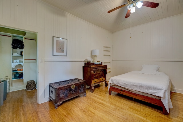 bedroom with ornamental molding, wooden walls, light hardwood / wood-style flooring, and ceiling fan