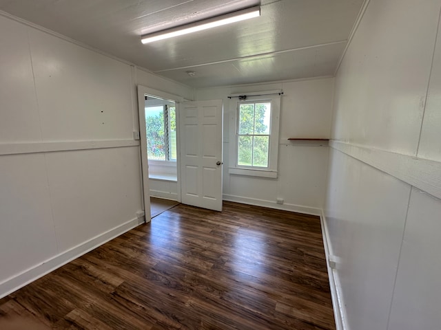 empty room with dark hardwood / wood-style flooring and crown molding