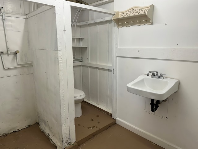 bathroom featuring sink, concrete floors, and toilet