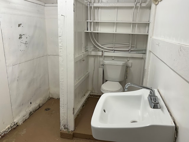 bathroom featuring sink, concrete flooring, and toilet