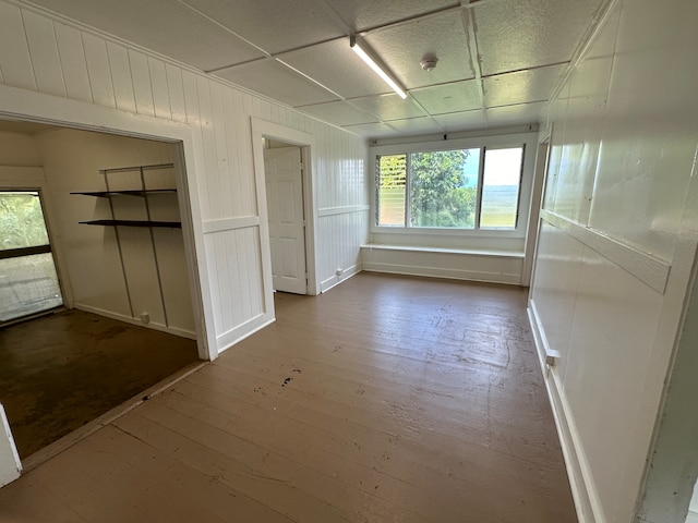 unfurnished room with hardwood / wood-style flooring, a drop ceiling, and a wealth of natural light